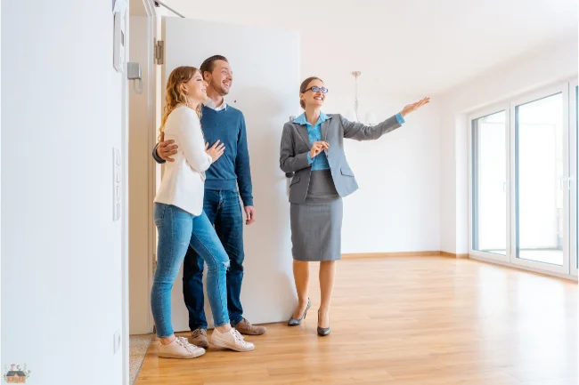 Mietmakler showing a couple around a rental property, explaining the features of the empty space.