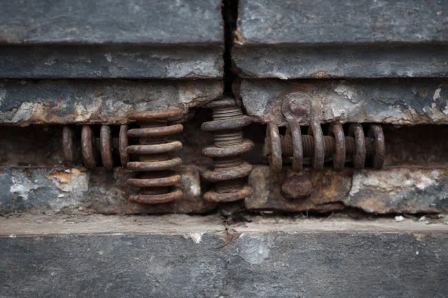 Garage Door Repair Bee Cave - Close-up of a broken garage door spring showing rust and damage.